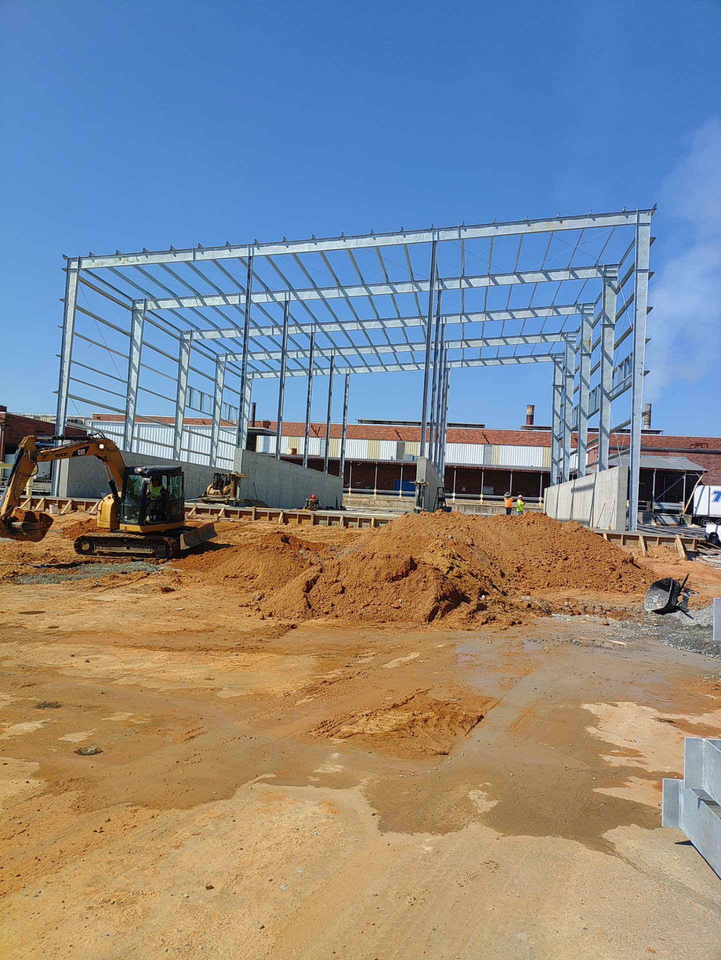 MIC Steel steel frame rising over a prepared site with an excavator at work
