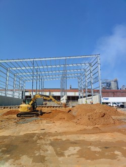 Excavator preparing the site beside a new steel building frame