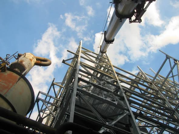 Structural steel framework and piping viewed from below at an industrial facility