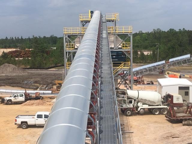 Long covered conveyor gallery running between industrial structures at a plant site