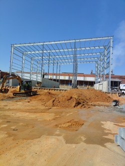 Steel building frame rising over a graded industrial site